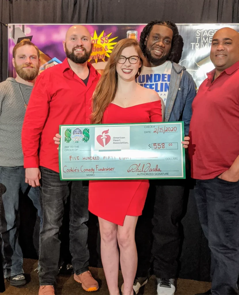 Group holding charity check at comedy fundraiser.