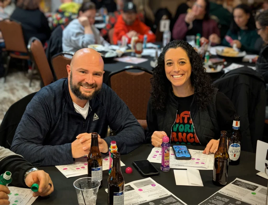 Smiling group at bingo event with drinks and papers.